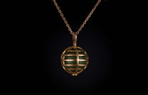William Henry necklace with green stone encased within a rose gold spherical cage.