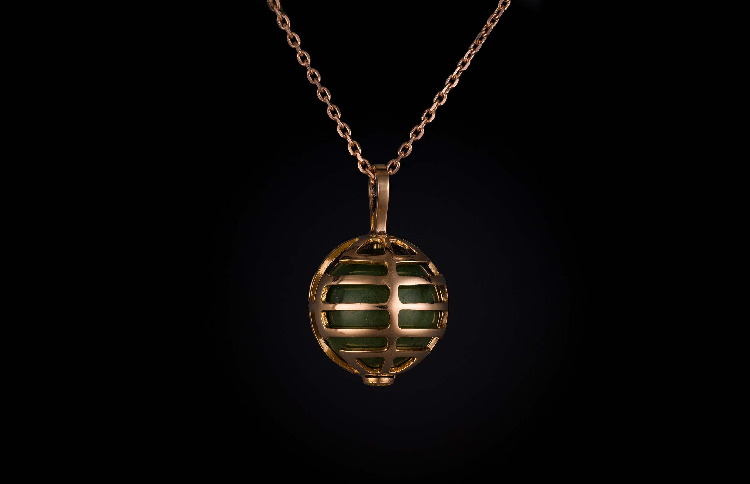 William Henry necklace with green stone encased within a rose gold spherical cage.