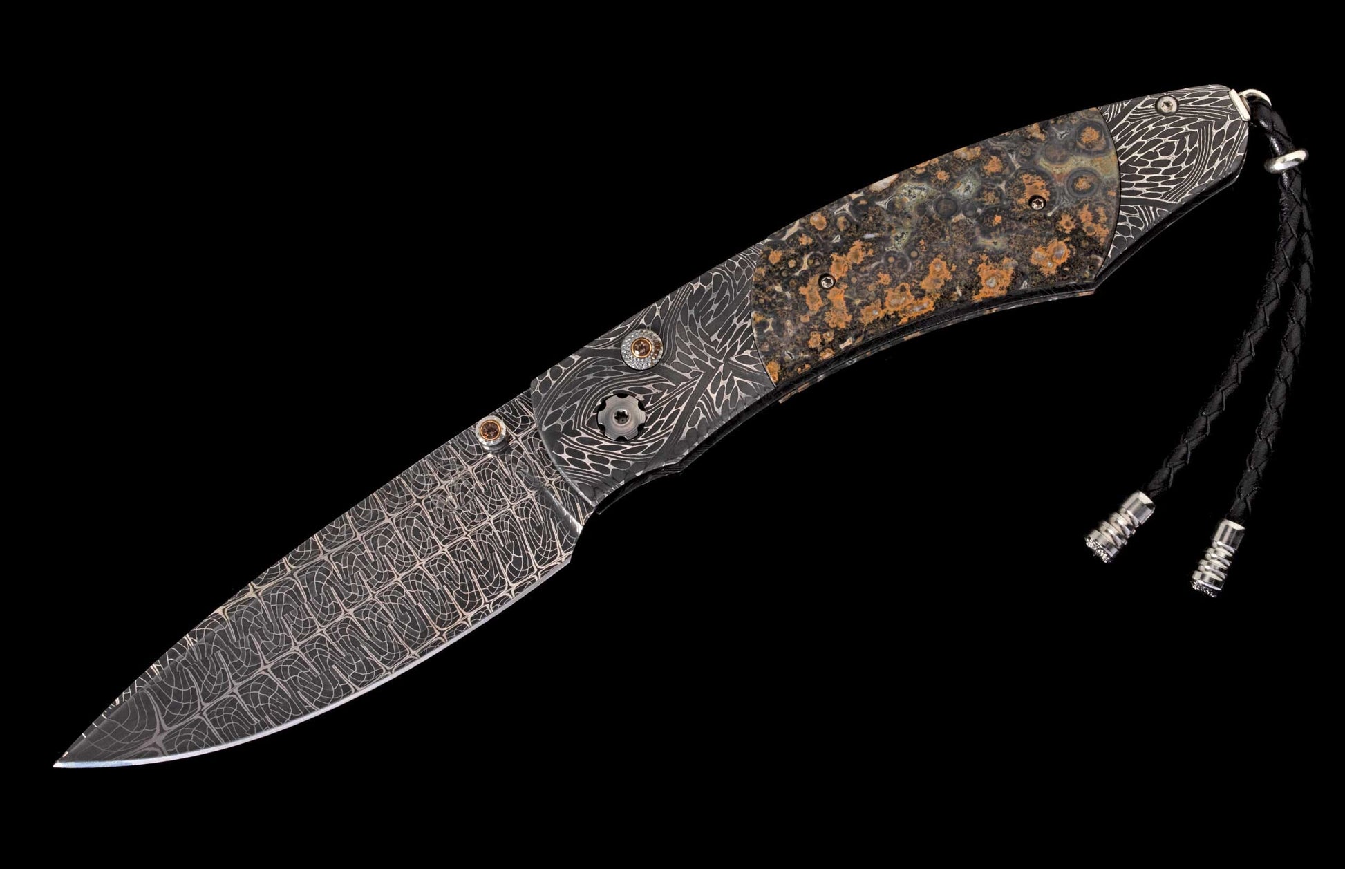 Folding knife with patterned Damascus blade and handle, mottled natural stone scales, decorative hardware, and braided leather lanyard.