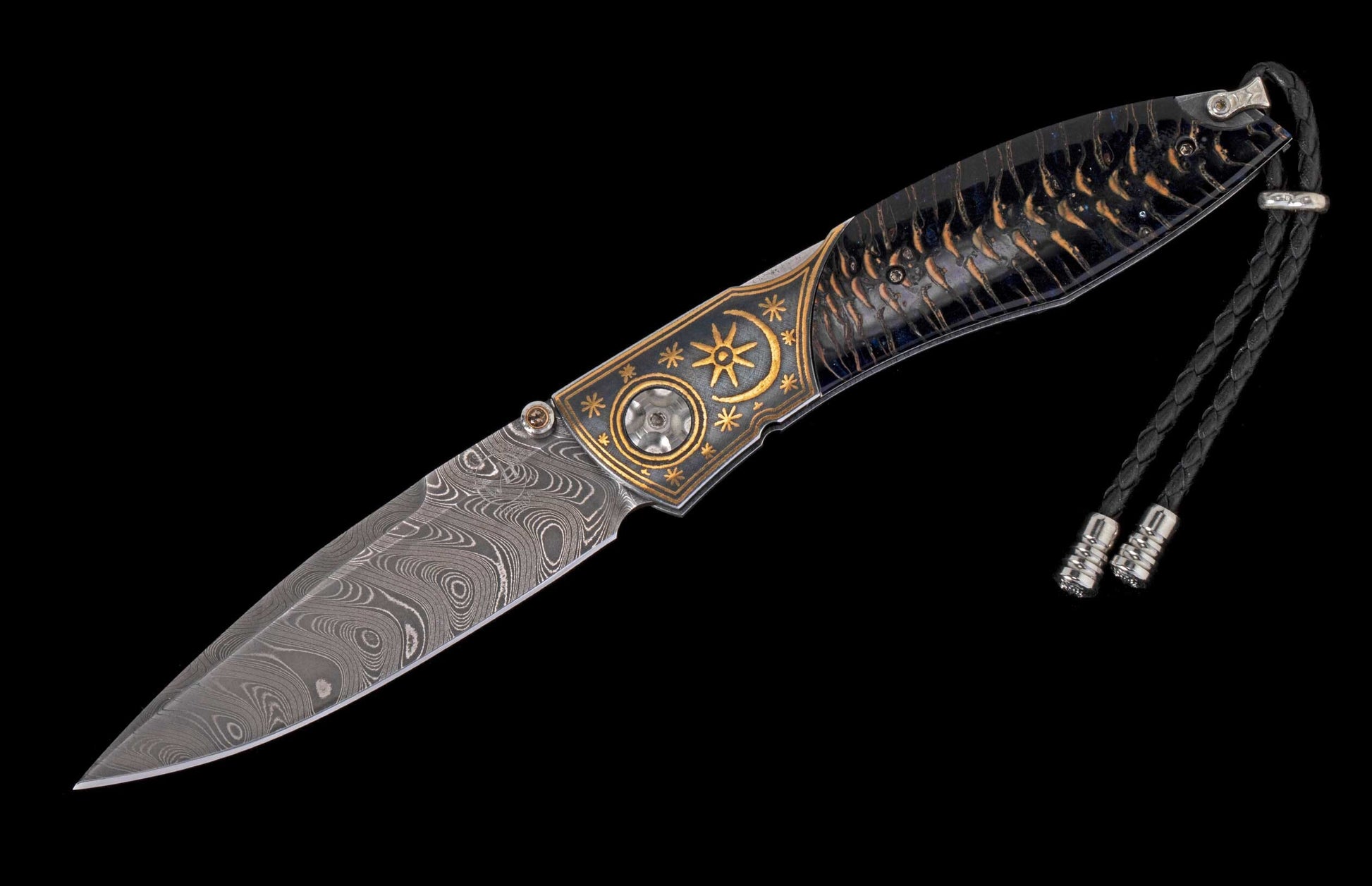 Folding knife with a Damascus steel blade, dark patterned handle with brass sun and star engravings, and braided leather lanyard.