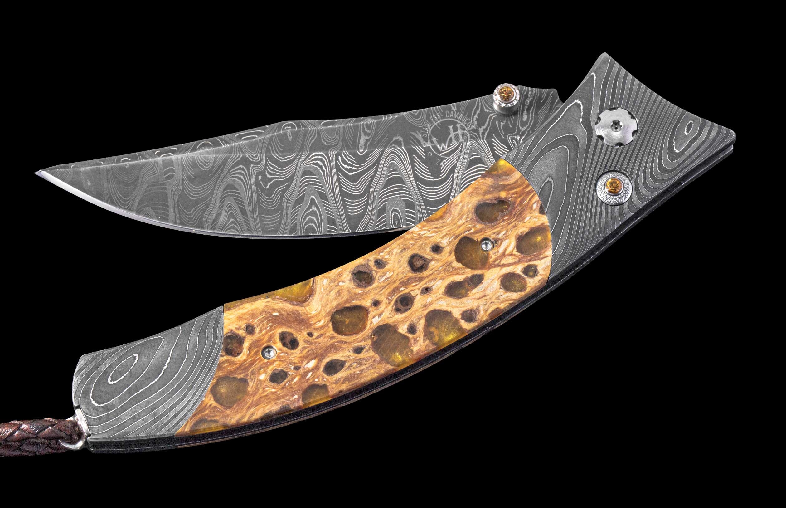 Damascus steel folding knife with a mottled brown and gold handle, ornate fasteners, and a braided leather cord, angled on black.