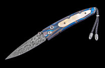 Diagonally angled folder knife with a stainless Damascus steel blade, a blue and gold patterned handle featuring a mother-of-pearl inlay, and a black braided leather lanyard.
