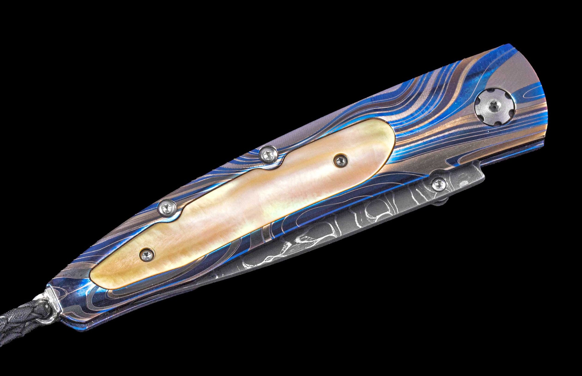 Blue, gold, and silver wave-patterned knife with mother-of-pearl inlay, decorative screws, and a black braided lanyard.