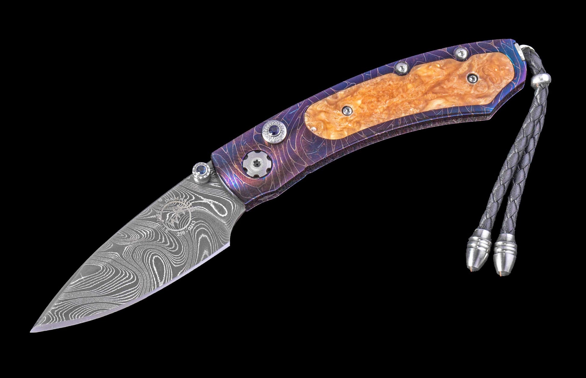 Folding knife with a swirling Damascus blade, iridescent purple and blue titanium handle with amber insert, and a braided leather lanyard.