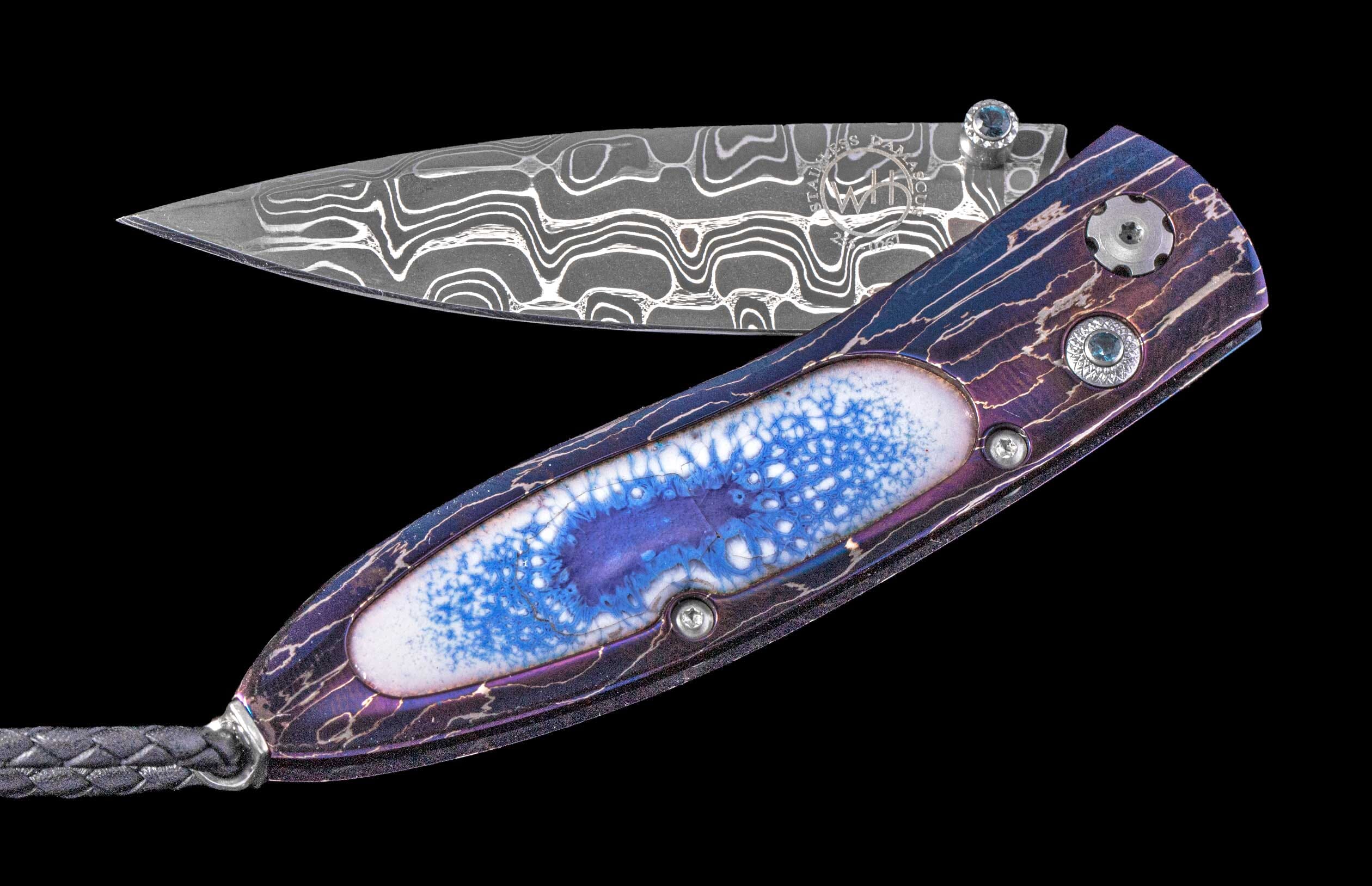Folding knife with a wavy patterned Damascus steel blade, an iridescent purple handle featuring a cracked white and blue inlay, and blue gem accents.
