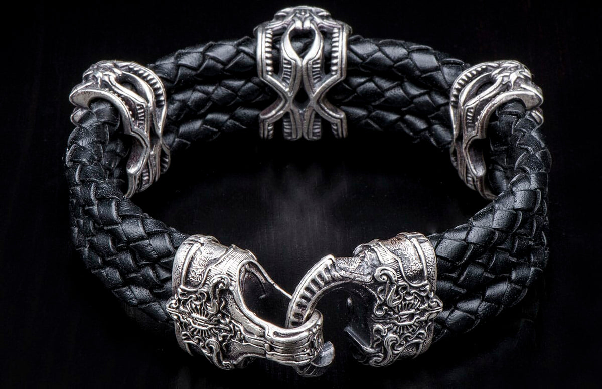 Black braided leather bracelet with elaborate silver-toned metal decorative beads and an intricately designed clasp.