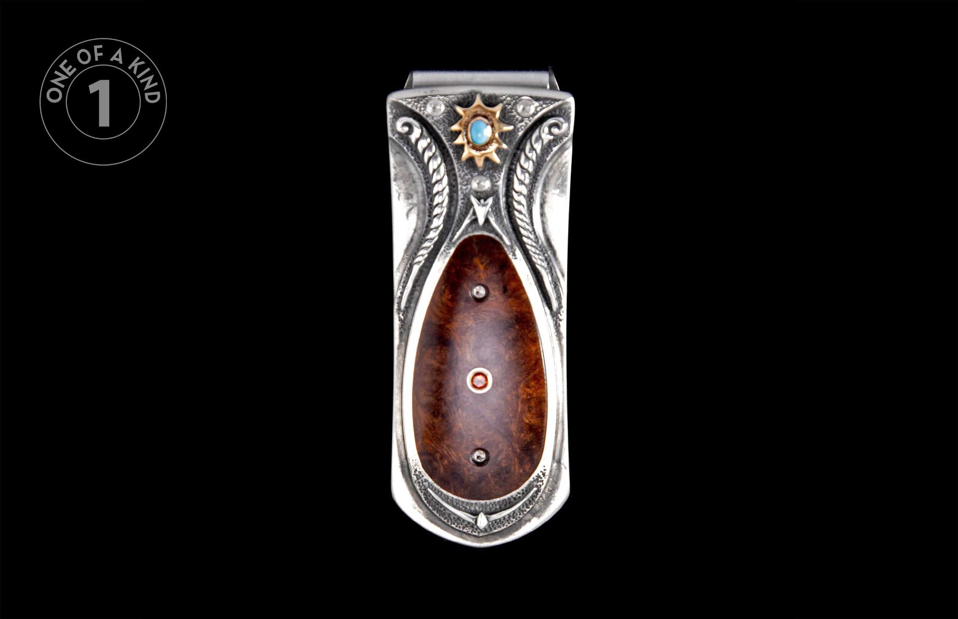 Ornate silver money clip with dark burled wood inlay, turquoise stone, and gold sunburst detail.