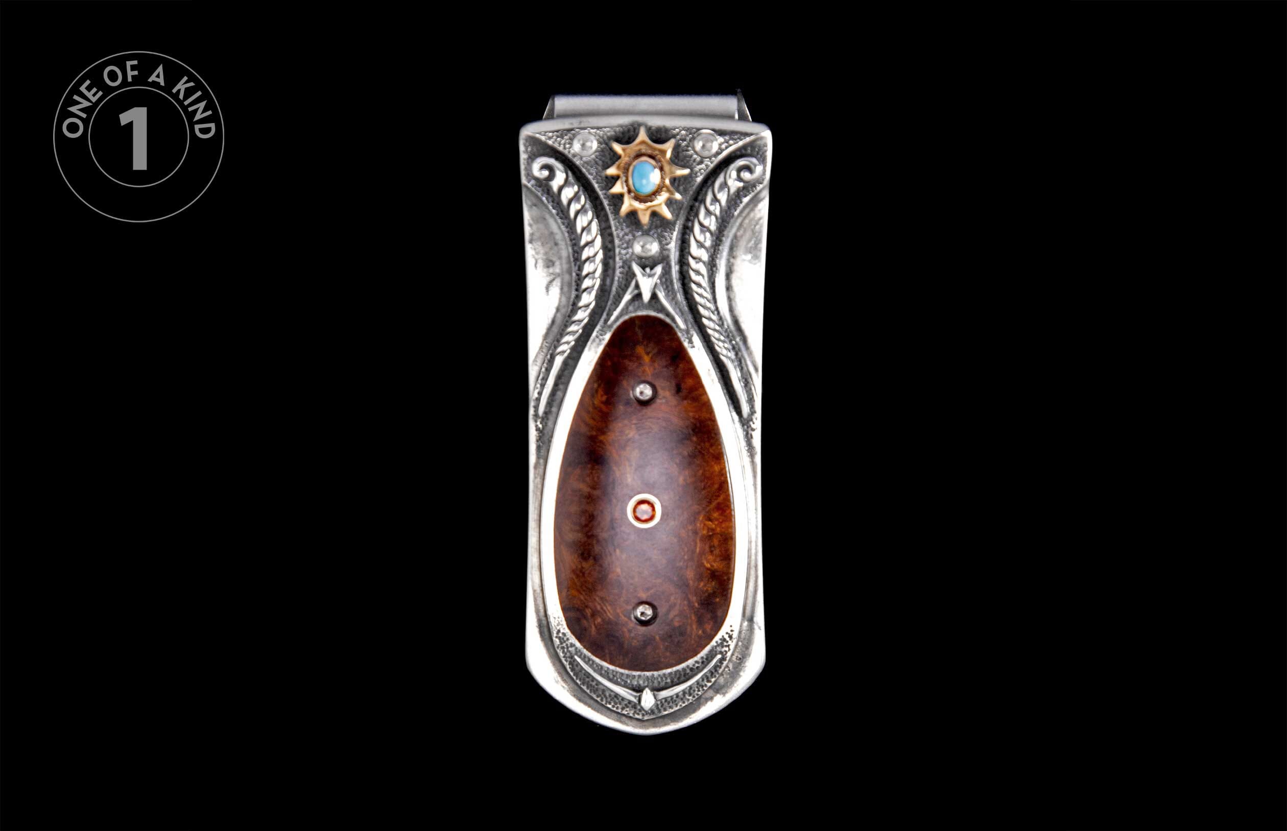 Ornate silver money clip with dark burled wood inlay, turquoise stone, and gold sunburst detail.