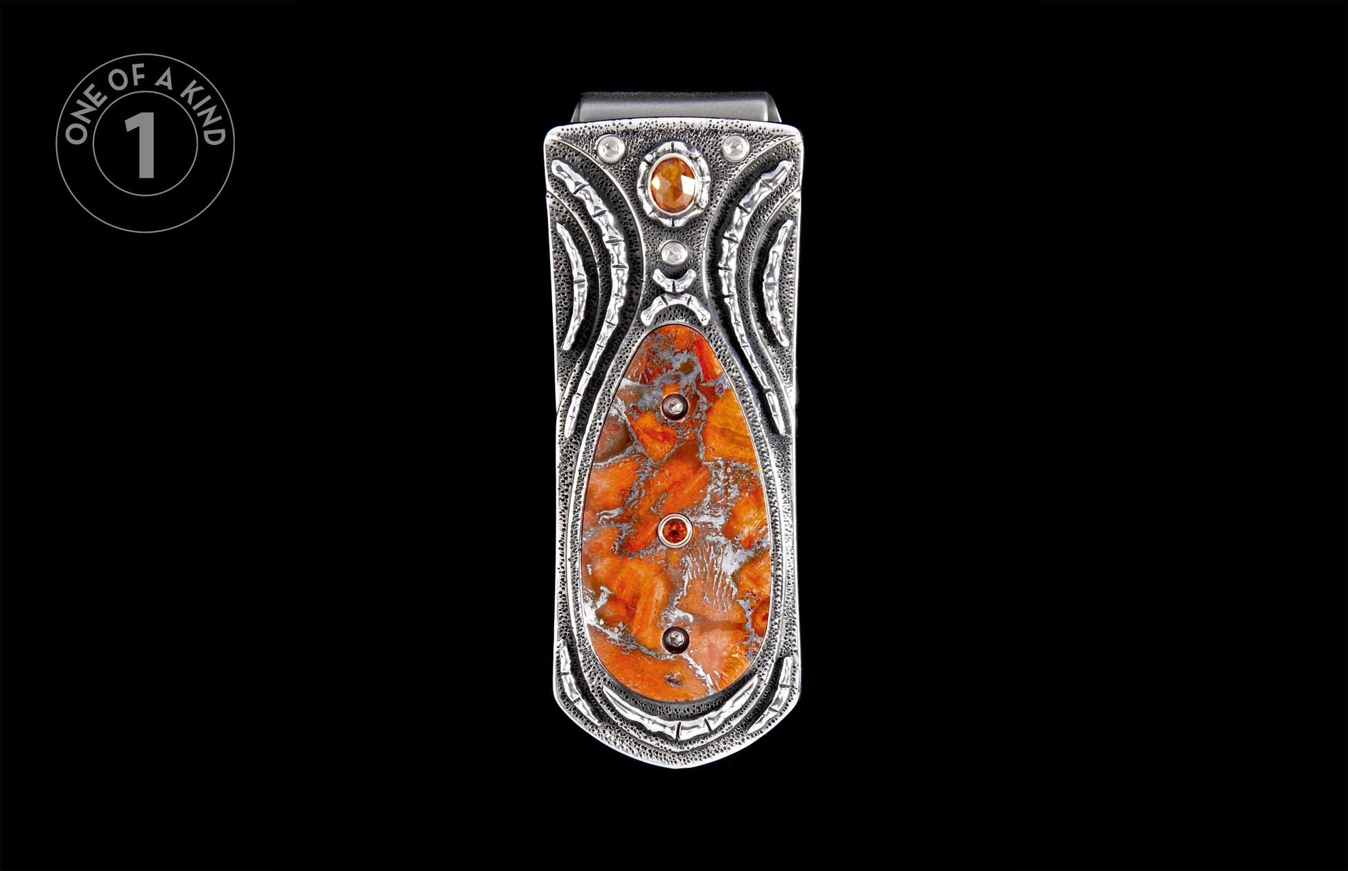 Silver money clip with an orange and white variegated stone inlay, featuring decorative etched patterns and small accent gems.
