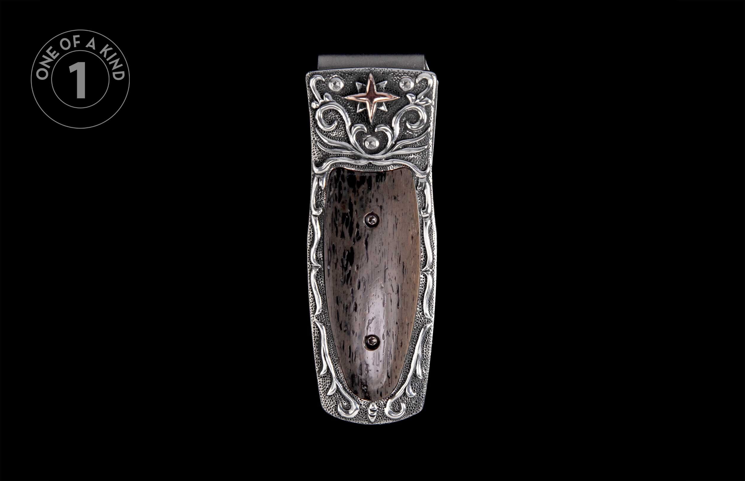 Silver-toned money clip with a pebbled background, dark textured insert, elaborate scrollwork, and a bronze star accent.