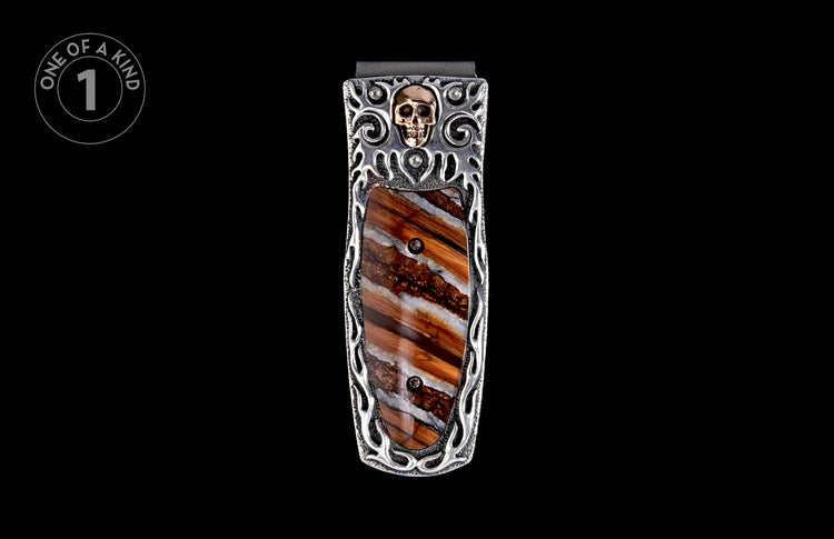 Money clip with a skull motif and brown striped inlay, featuring silver-toned metal with intricate scrollwork.