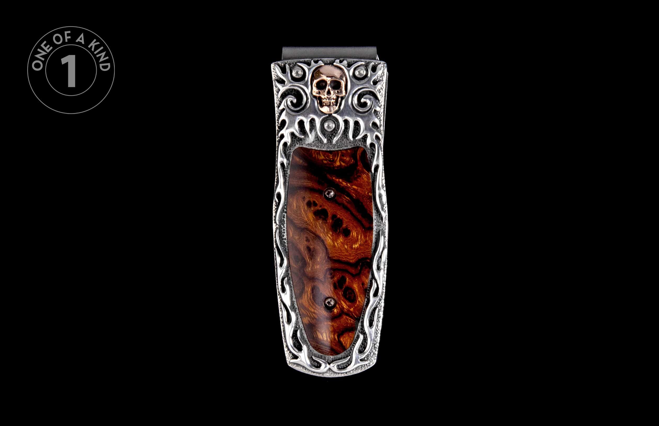 Silver-toned money clip with a brass skull, dark burl wood inlay, and ornate scrollwork details.
