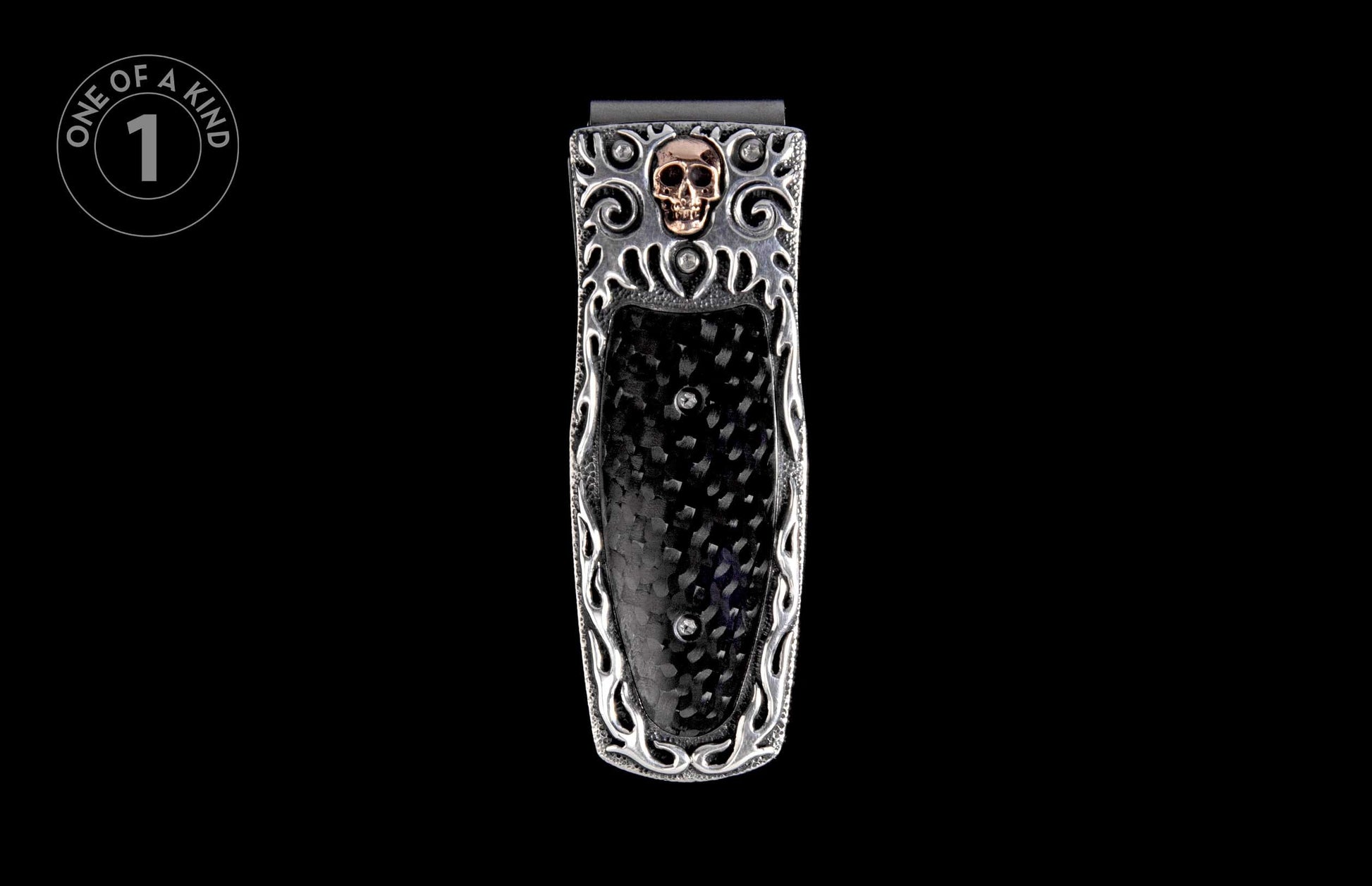 Silver money clip with a gold skull emblem, black carbon fiber inlay, and intricate silver scrollwork.