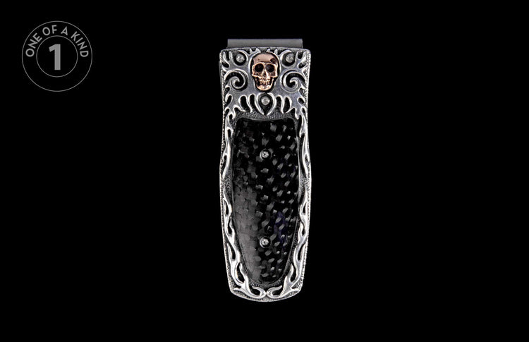Silver money clip with a gold skull emblem, black carbon fiber inlay, and intricate silver scrollwork.