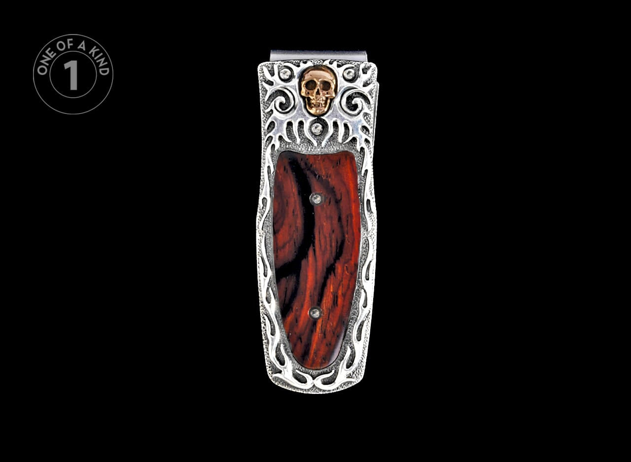 Silver-toned money clip with dark red wood inlay, featuring a gold skull and ornate silver frame.