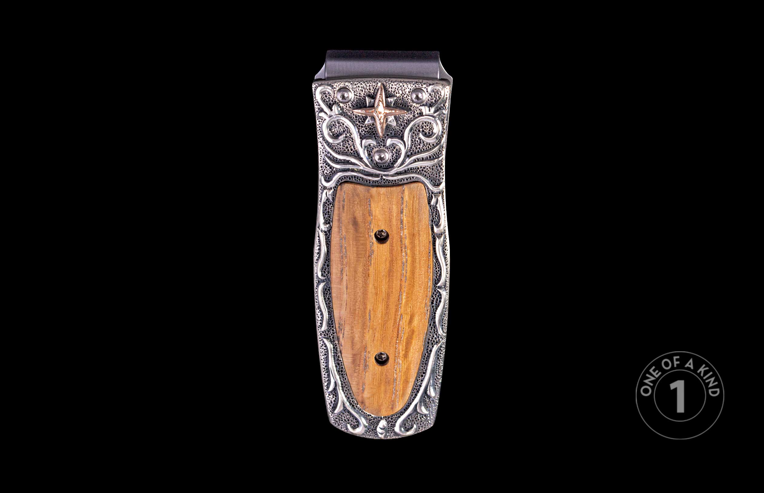 Ornate money clip with a silver-toned frame featuring scrollwork, stippling, a bronzed star, and a central polished brown wood inlay.