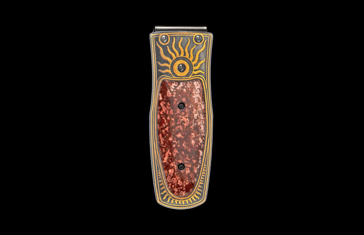 Money clip with dark metal frame, yellow sun and wave patterns, and mottled reddish-brown stone inlay.