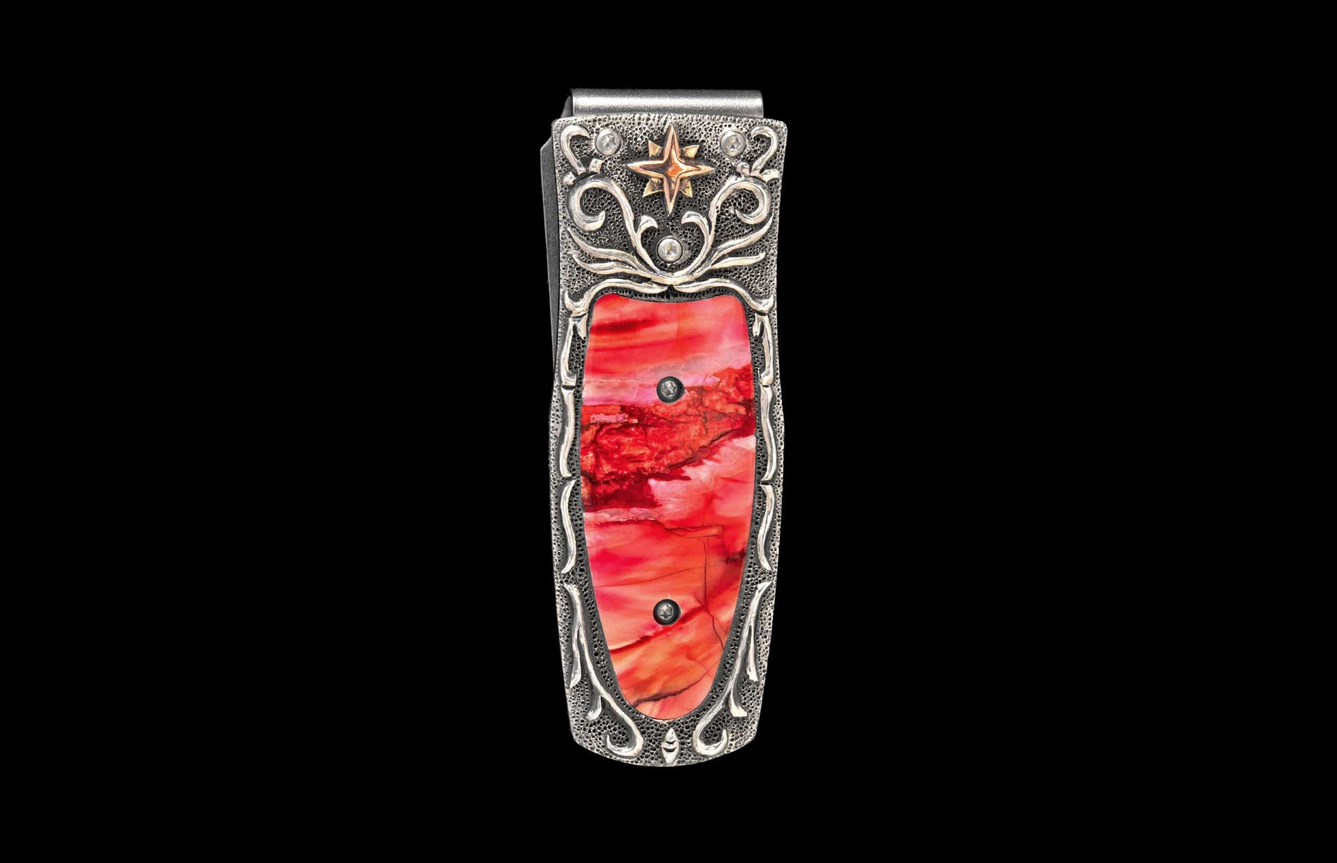 Silver money clip with a vibrant red inlay, adorned with intricate scrollwork, a gold star, and clear stones.