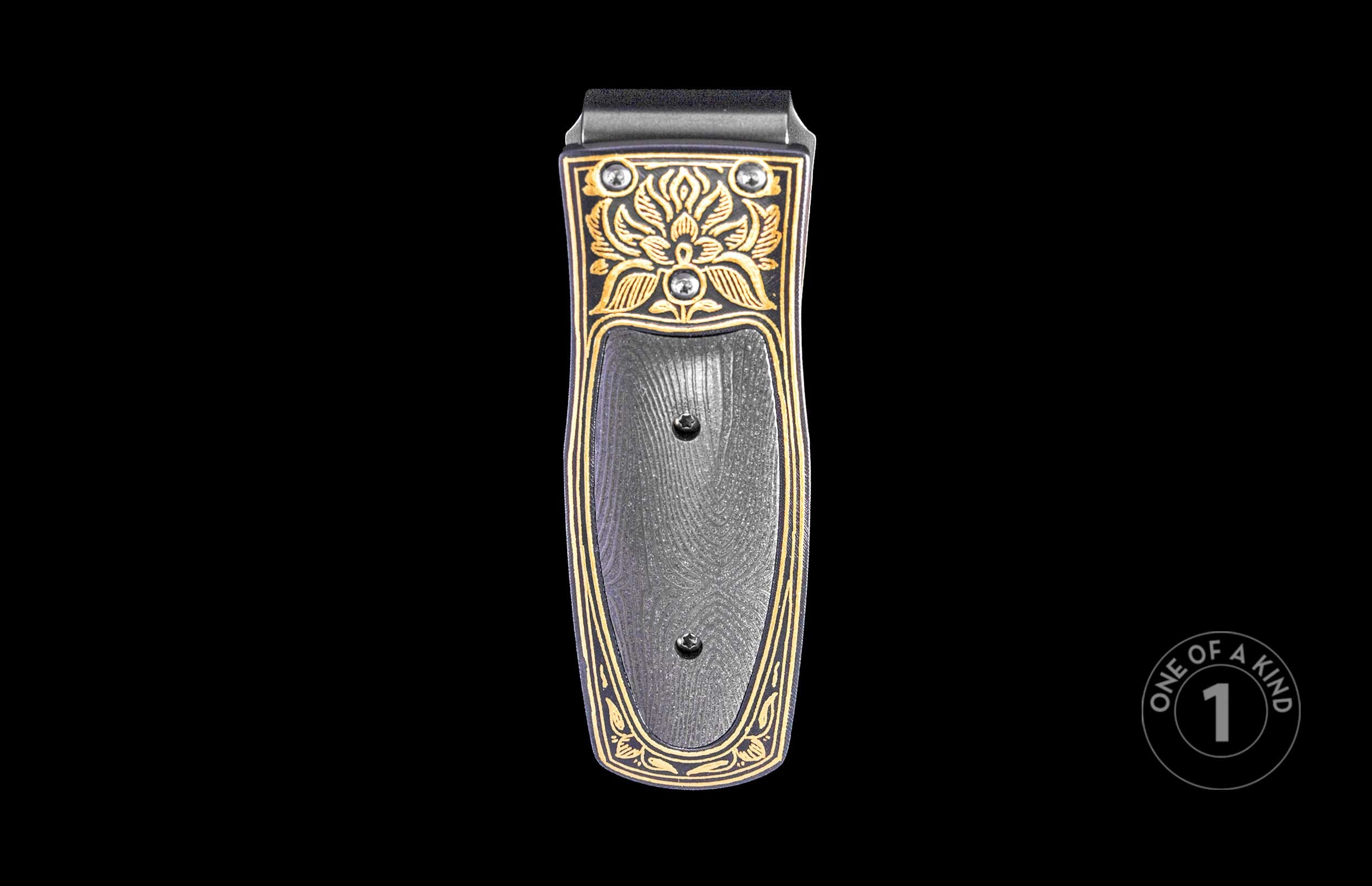 Black and gold money clip with ornate floral engravings, a textured center panel, two screws, and two round silver-toned accents.