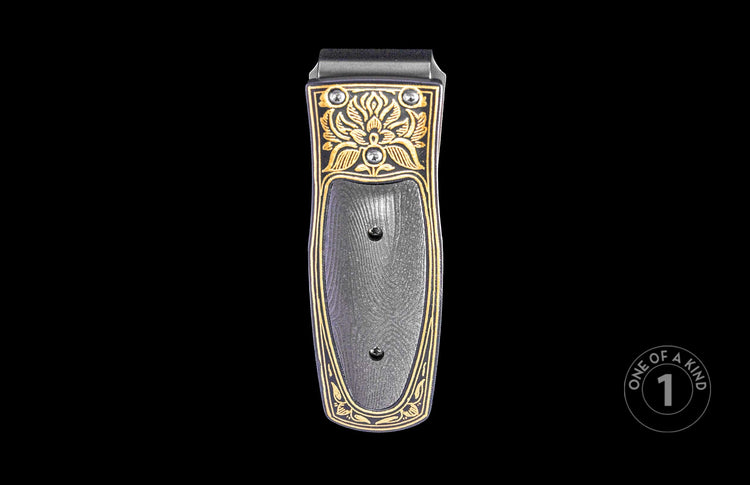 Black and gold money clip with ornate floral engravings, a textured center panel, two screws, and two round silver-toned accents.