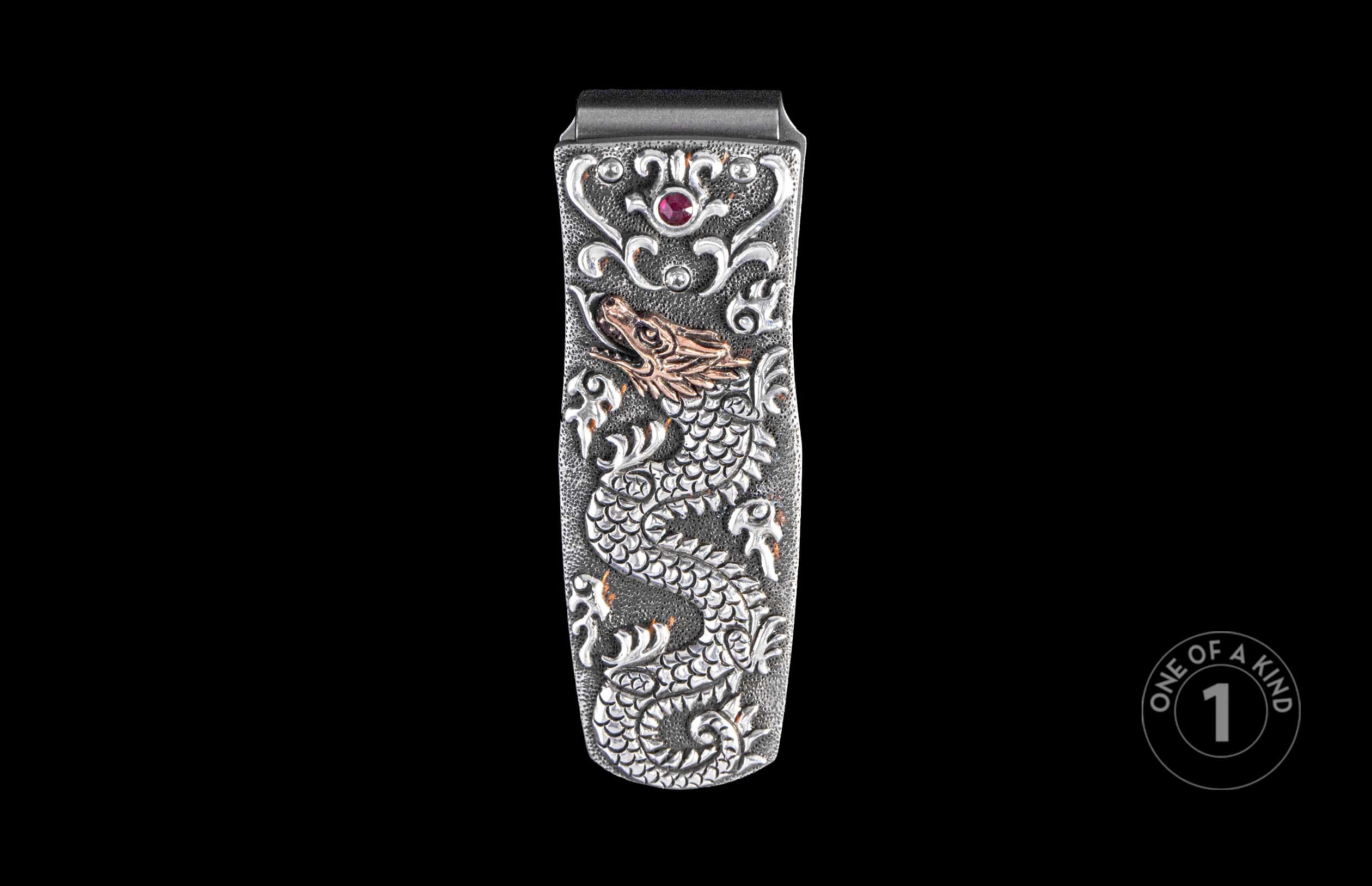 Silver-tone money clip featuring an embossed dragon, ornate scrollwork, a ruby-red gemstone, and a gold-tone dragon head.