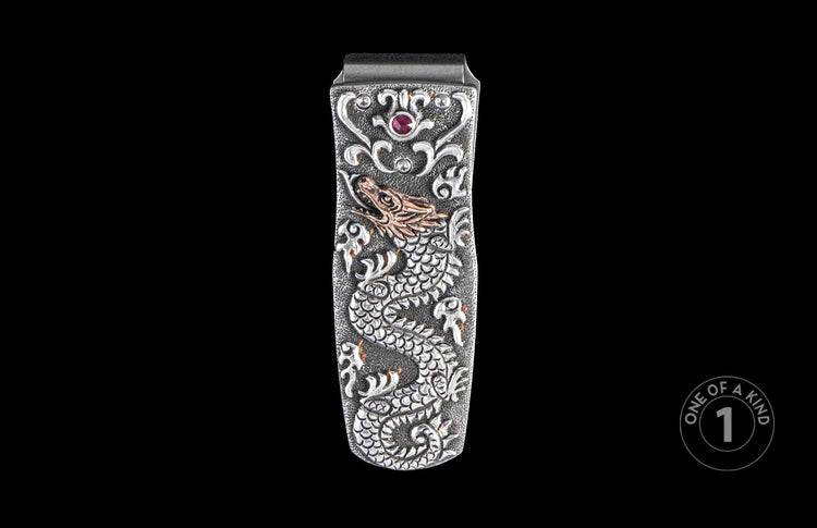 Silver-tone money clip featuring an embossed dragon, ornate scrollwork, a ruby-red gemstone, and a gold-tone dragon head.