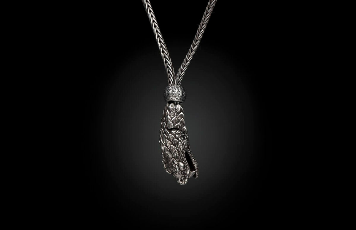 Silver braided necklace with an intricate dragon head pendant featuring scales.