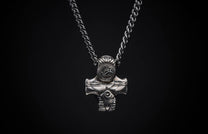Silver metal necklace with a braided chain and a detailed, hammer-style pendant featuring a circular 'WH' emblem and geometric carvings.