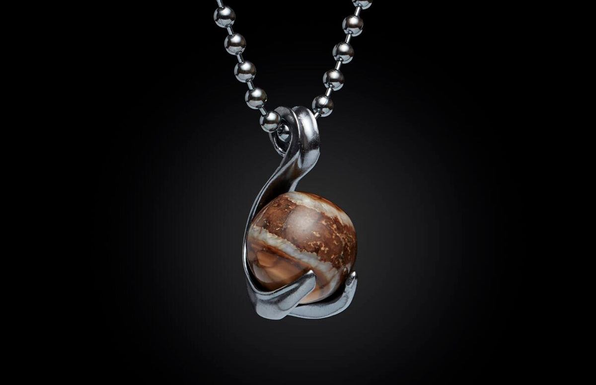 Round brown and white stone pendant in a silver-tone setting on a ball chain, against a black background.