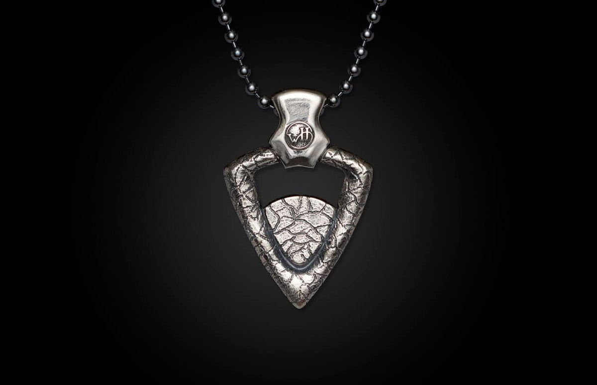 Silver-toned metal pendant necklace featuring a textured, arrowhead-shaped pendant with a small circular charm and a bead chain.