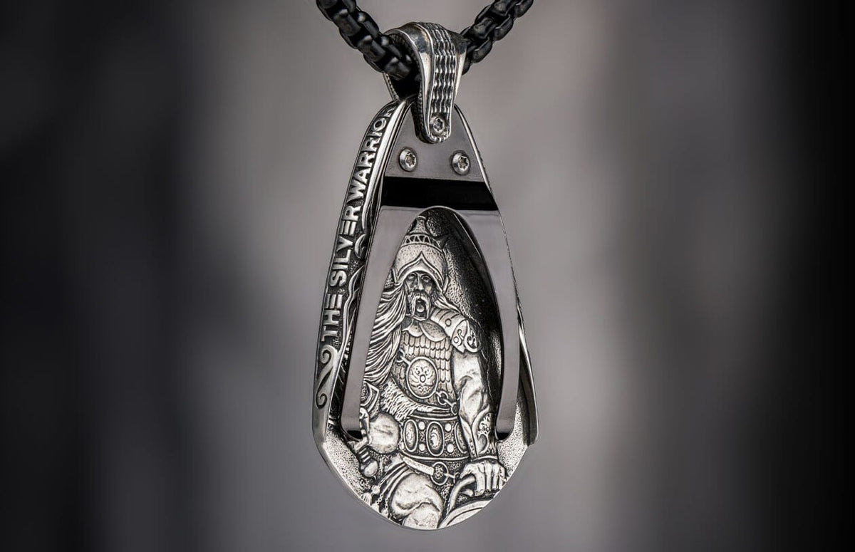 Silver pendant featuring an intricately detailed warrior figure and "THE SILVER WARRIOR" text on a black chain.