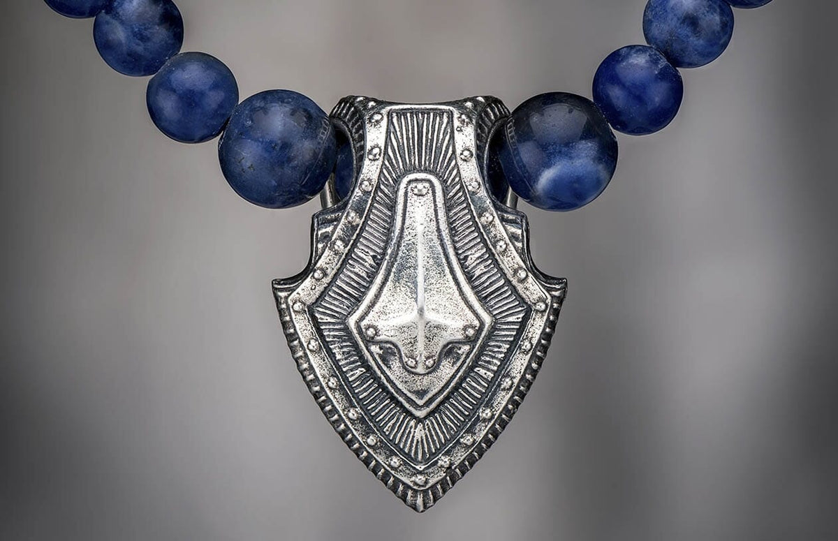 Sodalite shield pendant necklace in silver and blue sodalite, with intricate etched details.