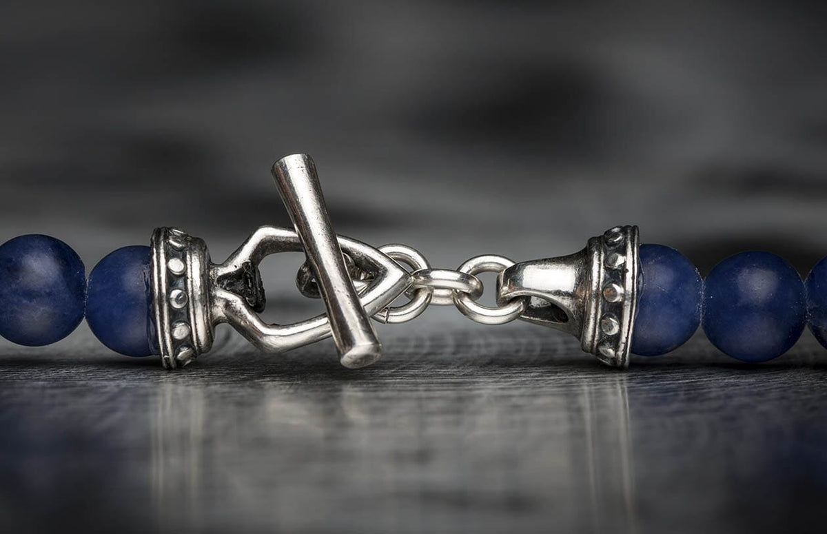 Sodalite bead bracelet with a silver metal toggle clasp, featuring ornate silver end caps and matte blue sodalite beads.