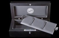 Beautiful wooden box that is custom fit to store or display your William Henry pocket knife. The box is stained a rich black and has silver hardware. A press of the single button opens the box on smooth hinges. Image displays the wooden box in an open pos