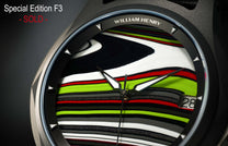 Fordite dial watch by William Henry, featuring vibrant striped pattern in black, white, red, and lime green, with polished silver hands and triangular hour markers, close-up view.