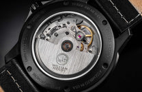 Black limited edition watch back by William Henry, showcasing Swiss movement with sapphire crystal and textured leather strap, side view.