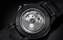 Black limited edition watch with exposed Swiss movement by William Henry, featuring sapphire crystal back and textured leather strap with white stitching.
