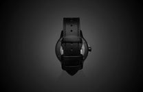Special Edition Fordite watch by William Henry, black leather strap, matte finish case, back view on dark gradient background