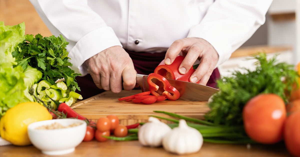 Chef cutting red pepper with kitchen knife