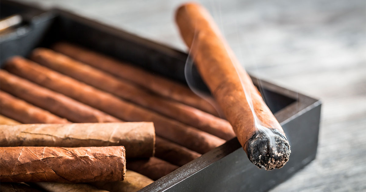 Lit cigar on top of cigar box
