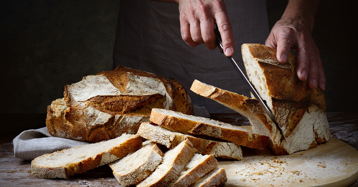 Man cutting bread with kitchen knife