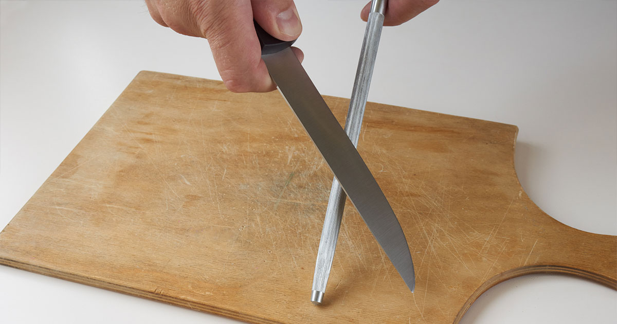 Sharpening kitchen knife on cutting board