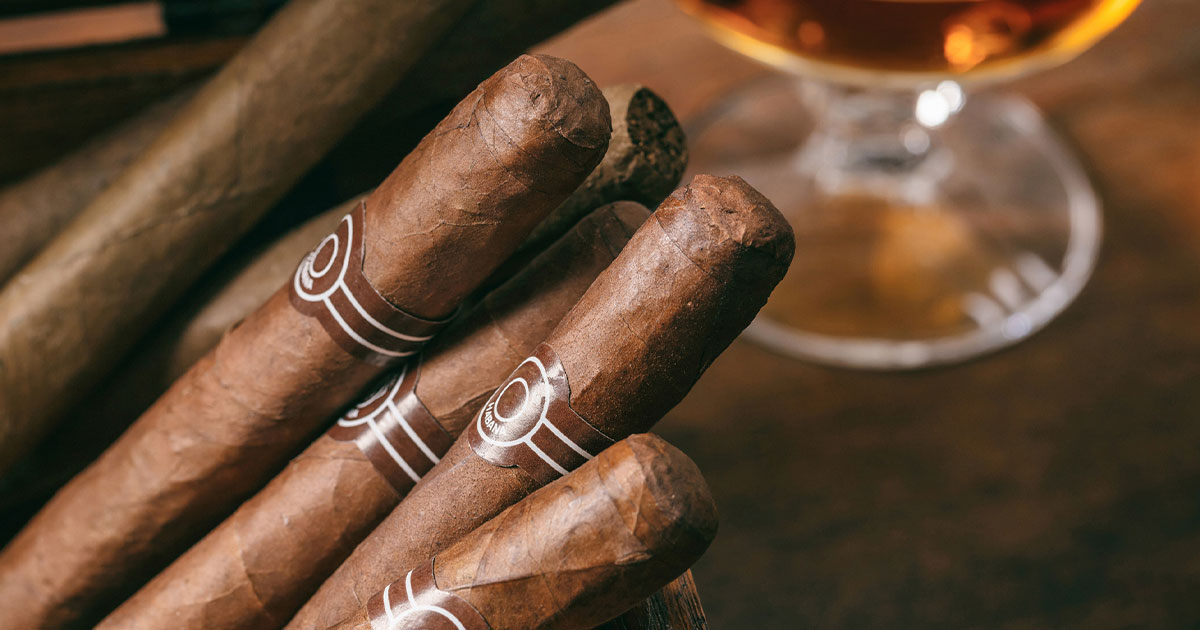 Stack of cigars next to whiskey glass