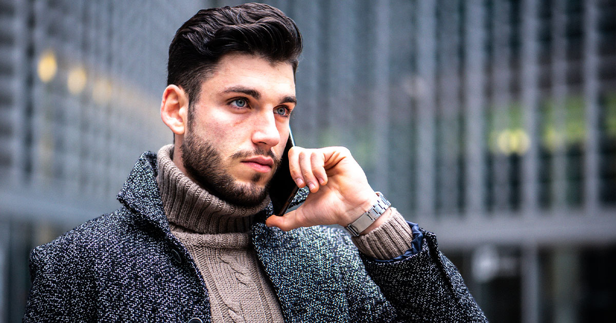 Man in turtle neck and cardigan on phone