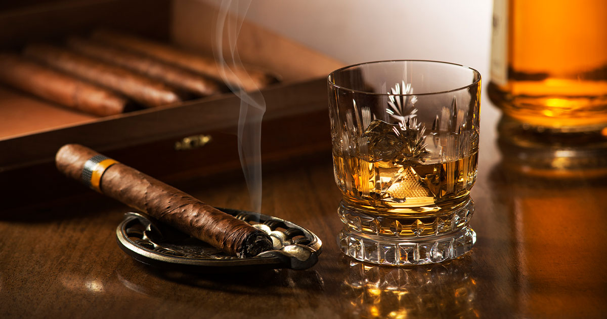 Lit cigar paired with whiskey