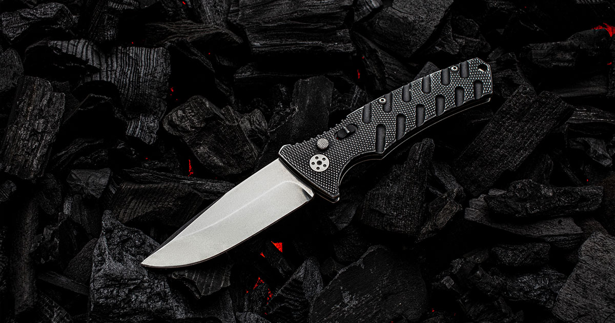 Black folding pocket knife on burning coals